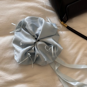 Vue détaillée d'un chouchou en satin bleu clair avec perles et rubans sur tissu blanc