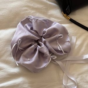 Détail de chouchou en satin lavande avec des petits nœuds blancs et des perles