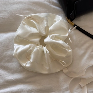Détail du chouchou en soie blanche orné de perles élégantes et d'un long nœud ruban