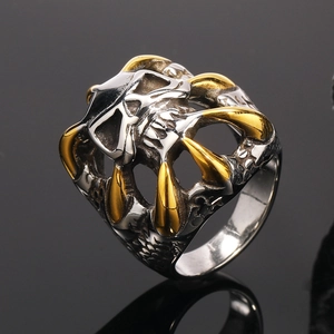 Dettaglio macro di anello teschio punk con artigli d'aquila dorati in acciaio argento