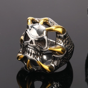 Dettaglio macro dell'anello teschio punk con artigli d'aquila dorati e texture a scaglie