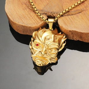 Japanese Oni mask pendant necklace in gold finish with red gem eye on wooden stand