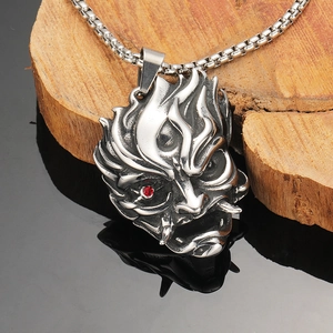Macro shot of silver Hannya mask pendant featuring a red gemstone eye and bone texture