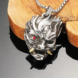 Detail of Hannya mask pendant with red eye and golden tusks on a rustic wood block