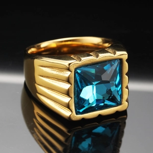 Dettaglio anello da uomo in titanio dorato con pietra blu quadrata e lati a strisce