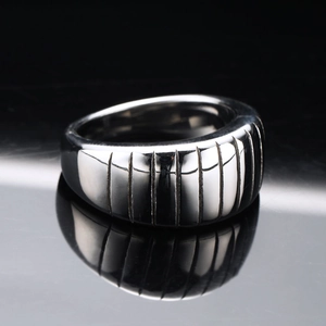 Industrial style silver stainless steel ring with vertical grooves on a black reflection