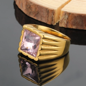Dettaglio della pietra quadrata rosa su anello in acciaio al titanio dorato con texture