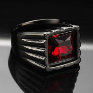 Dettaglio macro di un anello da uomo in titanio nero con grande zircone rosso quadrato