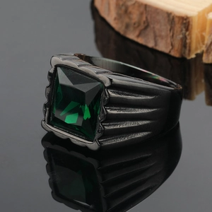 Dettaglio macro di un anello da uomo in titanio nero con pietra quadrata verde smeraldo