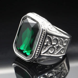 Macro shot of men's titanium steel ring with emerald gemstone and engraved side patterns
