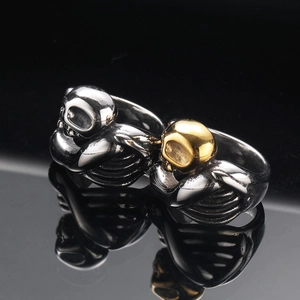 Gothic skull rings in silver and gold steel finish on a sleek black reflective surface