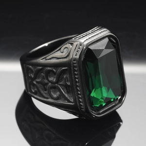 Macro detail of men's vintage black steel ring with engraved patterns and green gemstone