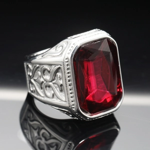 Macro shot of a men's steel ring featuring a large red gemstone and vintage side engravings
