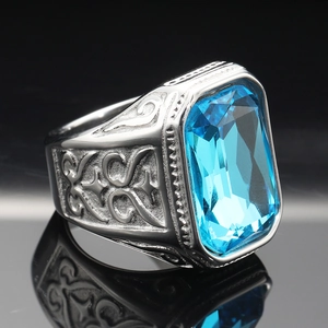 Macro shot of men's vintage steel ring with large rectangular blue gemstone and floral carving