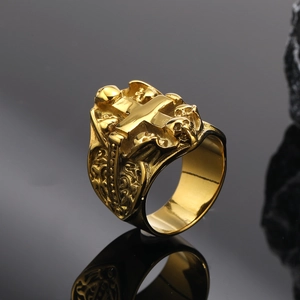 Gros plan d'une bague pour homme avec tête de mort et croix en or sur fond sombre