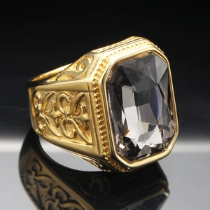 Macro shot of gold-plated men's ring with large emerald-cut black gemstone and relief details