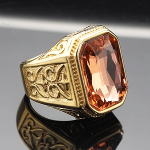 Macro detail of luxury gold titanium ring with a large faceted orange-red gemstone inlay