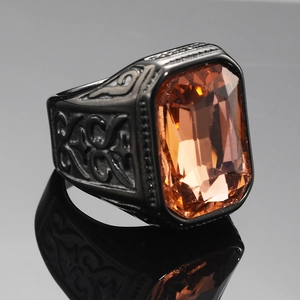 Macro detail of men's black stainless steel ring with a large amber gemstone and engravings