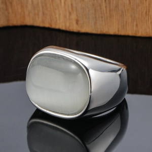 Close-up of wide silver band ring featuring a large oval translucent white cat eye stone