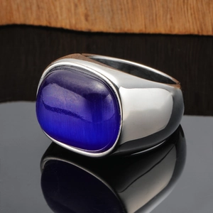 Macro detail of a wide band silver ring featuring a large oval blue cat's eye stone inlay