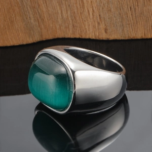 Detailed macro view of wide band ring featuring a large green cat eye stone on black surface