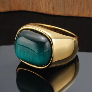 Macro close-up of large oval green cat-eye stone on polished gold-tone wide ring band