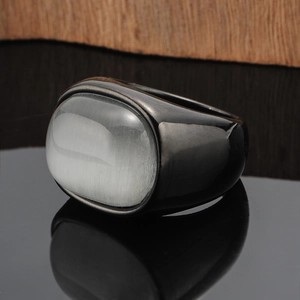 Detailed view of heavy gunmetal ring with oval cat's eye stone on reflective surface
