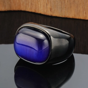 Macro shot of wide black metal ring with a purple cat-eye stone on wood background