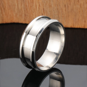 Polished stainless steel ring with a central brushed groove on a wood background