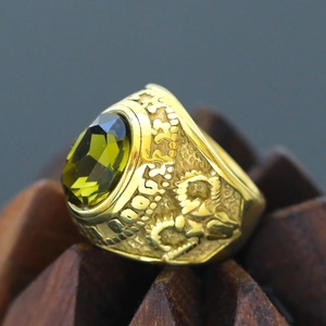 Macro detail of retro golden men's ring with oval green gemstone and ornate carvings