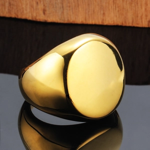 Polished gold stainless steel signet ring with a flat oval surface on black reflection