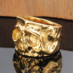 Close-up van goudkleurige schedelring met punk lava textuur en metalen reflectie