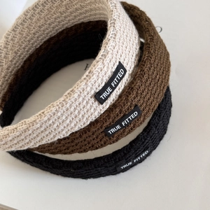 Detailed view of wide knitted headbands in beige, brown and black with True Fitted labels