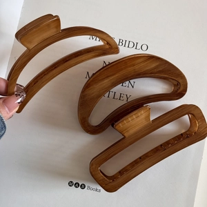 Close-up of three brown wood texture hair claws in different shapes on a magazine
