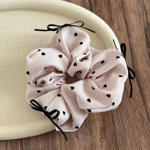 Detailaufnahme von rosa Haargummi mit schwarzen Herzen und Schleifen auf einem Tablett