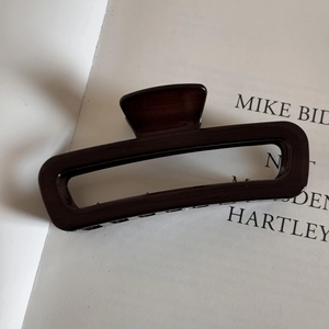 Close-up of a large tortoiseshell resin hair claw clip resting on a minimalist book page