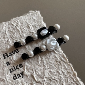 Detail of French vintage hair clips with pearls, black beads and white rose on paper