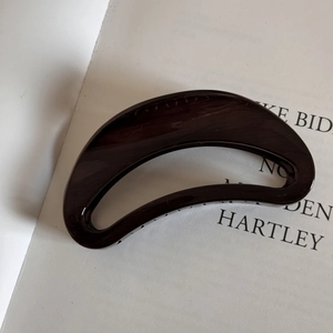 Detailed view of large dark brown wood grain textured semi-circle hair claw clip