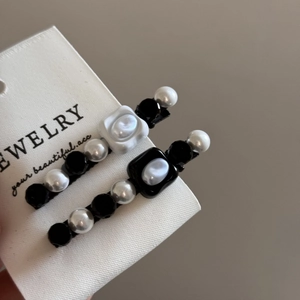 Close-up of French vintage hair clips with black and white pearls on textured card