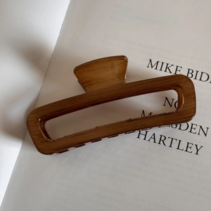 Detail of large brown wood grain hair claw clip on a minimalist magazine background