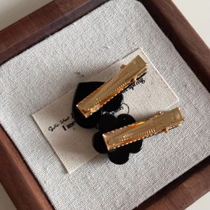 Détail de barrettes à cheveux en résine noire en forme de cœur et de fleur dorées