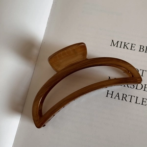 Detail of a large semi-circle hair claw clip with vintage brown wood grain texture