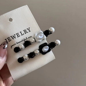 Detail of elegant black and white faux pearl hair clips set on a display card