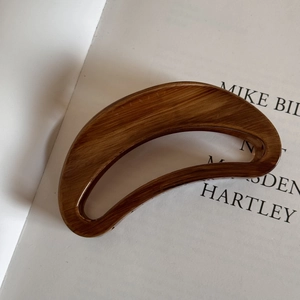 Detailed view of large dark brown wood grain textured hair claw clip with cutout design
