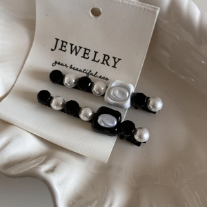 French retro hair clips set with pearls and black beads on white ceramic tray