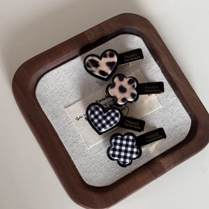 Détail de quatre barrettes à motifs léopard et à carreaux sur un plateau en bois
