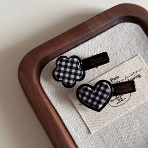 Vue détaillée des barrettes à motif damier en forme de fleur et de cœur sur plateau