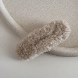 Detailansicht der flauschigen Lammwolltextur an der haferfarbenen Haarspange
