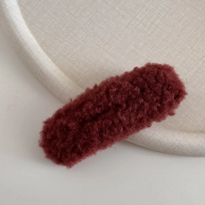 Nahaufnahme der flauschigen burgunderroten Plüschtextur einer großen Haarspange