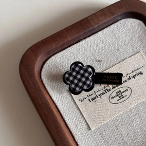 Détail de la pince à cheveux à fleurs à carreaux avec texte France Handmade sur noir